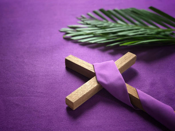 A religious cross and palm leaves on purple background.